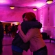 Two people hug in gallery space.