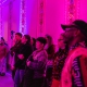 A rapt audience awash in fuchsia light.