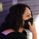Angie Cruz listens intently while wearing a black face mask. 