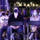 A row of masked audience members watch.