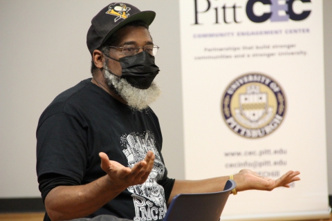 Joel Dias-Porter in a baseball cap and face mask, gesturing